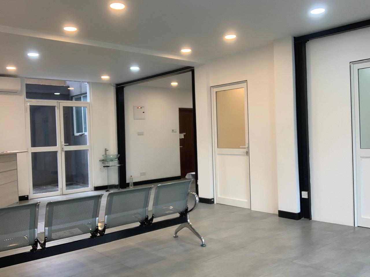 White clinic waiting area with metal seating and glass doors